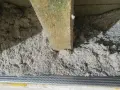 Drewniana belka w luźnej, szarej masie. To celuloza ocieplenie, które zapewnia komfort termiczny.