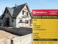 Tablica informacyjna budowy domu w trakcie budowy, z widocznym rusztowaniem i fundamentami. Na tablicy dane inwestora i numer telefonu alarmowego.