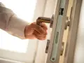 Dłoń naciska klamkę, odsuwając zasuwy drzwi.