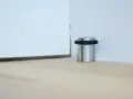 Metalowy odbojnik z czarną gumką przy ścianie, chroniący drzwi przed uderzeniem.