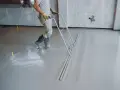 Robotnik wyrównuje świeżą wylewkę betonową. Sprawdź wylewka betonowa cena za m2 robocizny bez materiału.