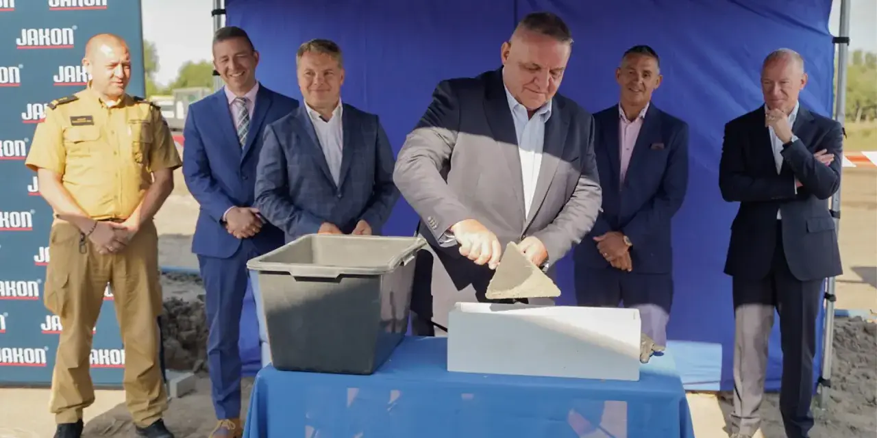 Uroczyste wmurowanie kamienia węgielnego. Mężczyzna w garniturze z kielnią w dłoni symbolicznie rozpoczyna budowę.