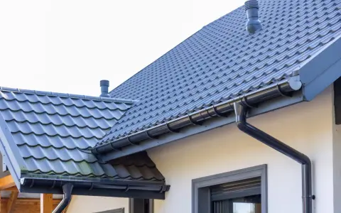 Szary dach z dachówki ceramicznej, idealny do obliczenia dachówka ceramiczna cena za m2. System rynnowy odprowadza wodę.