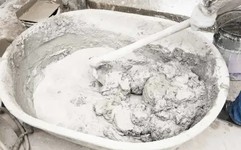 Mieszanie wapna gaszonego w dużej kadzi, tworząc gładką masę do prac budowlanych.