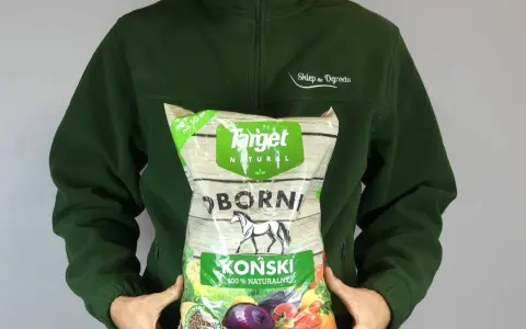 Osoba w zielonej bluzie trzyma worek z napisem "OBORNIK KOŃSKI GRANULOWANY". Idealny do ogrodu.