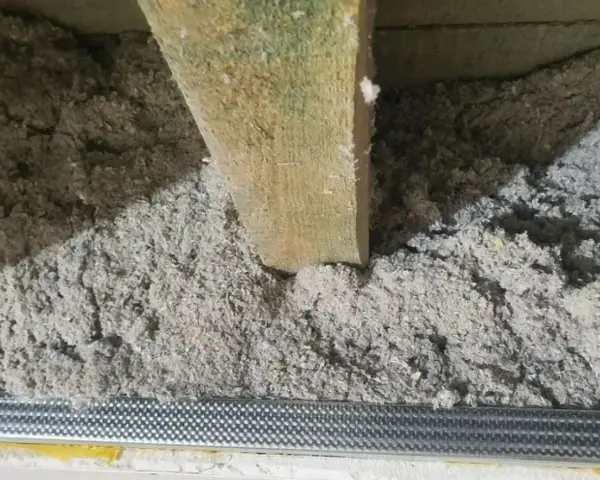 Drewniana belka w luźnej, szarej masie. To celuloza ocieplenie, które zapewnia komfort termiczny.