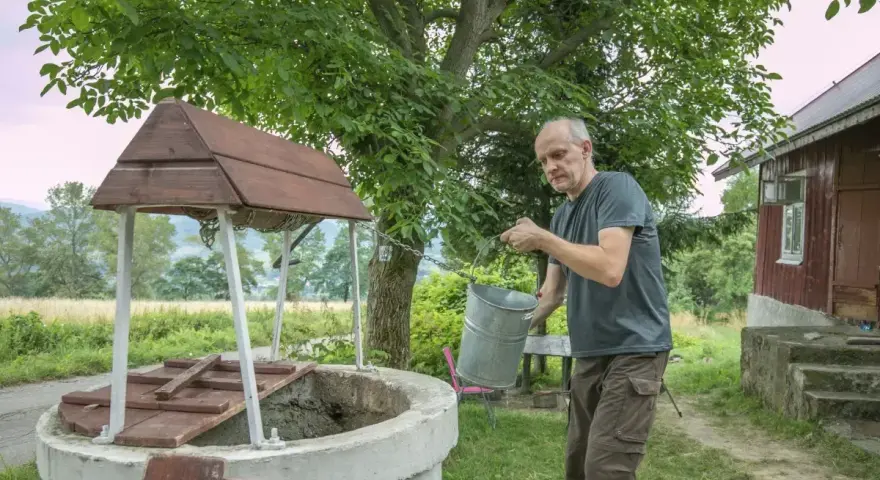 Mężczyzna czerpie wodę z **studni głębinowej**. Czy posiada **pozwolenie** na jej budowę?