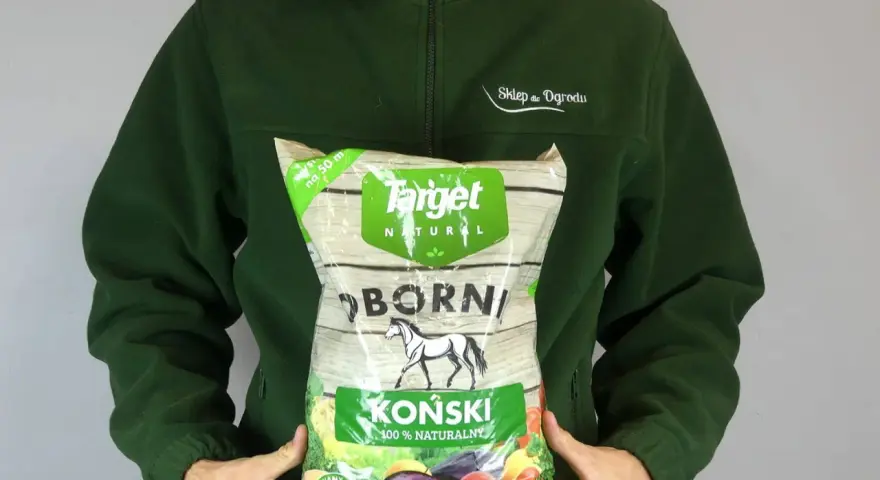 Osoba w zielonej bluzie trzyma worek z napisem "OBORNIK KOŃSKI GRANULOWANY". Idealny do ogrodu.