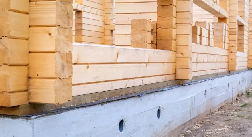Budowa domu z bali w 2025 roku. Fundament i ściany z drewna w trakcie wznoszenia.
